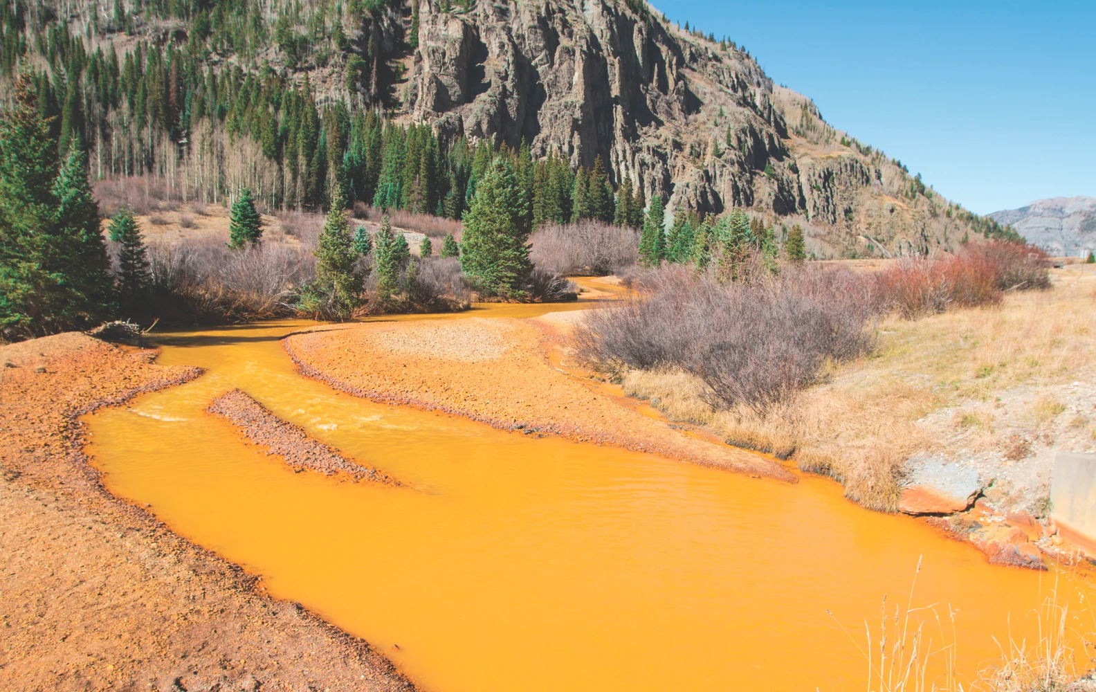 River runs red with mine tailings, severely impacting the aquatic ecosystem.
