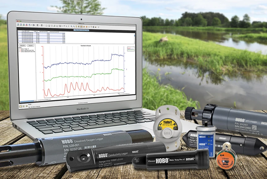 A laptop and a collection of HOBO data loggers beside a lake